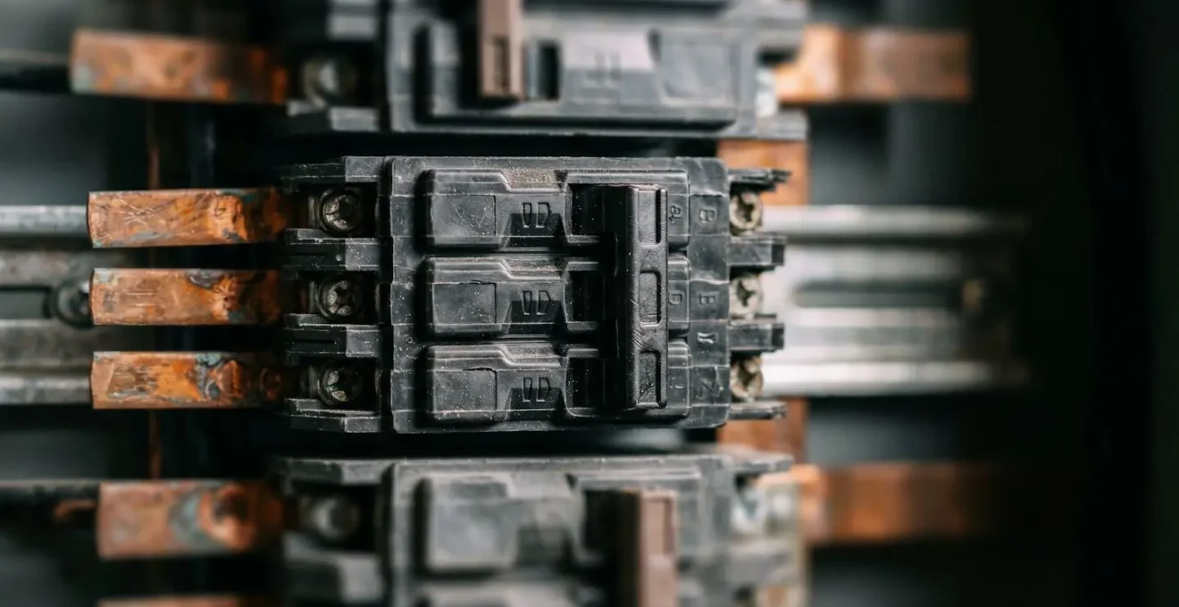 Vue détaillée macro d'un tableau électrique triphasé montrant la répartition équilibrée des circuits sur trois phases