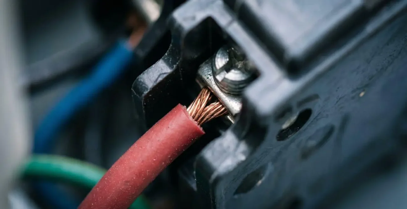 Gros plan macro sur les connexions et disjoncteurs d'un tableau électrique résidentiel lors d'une inspection visuelle de maintenance